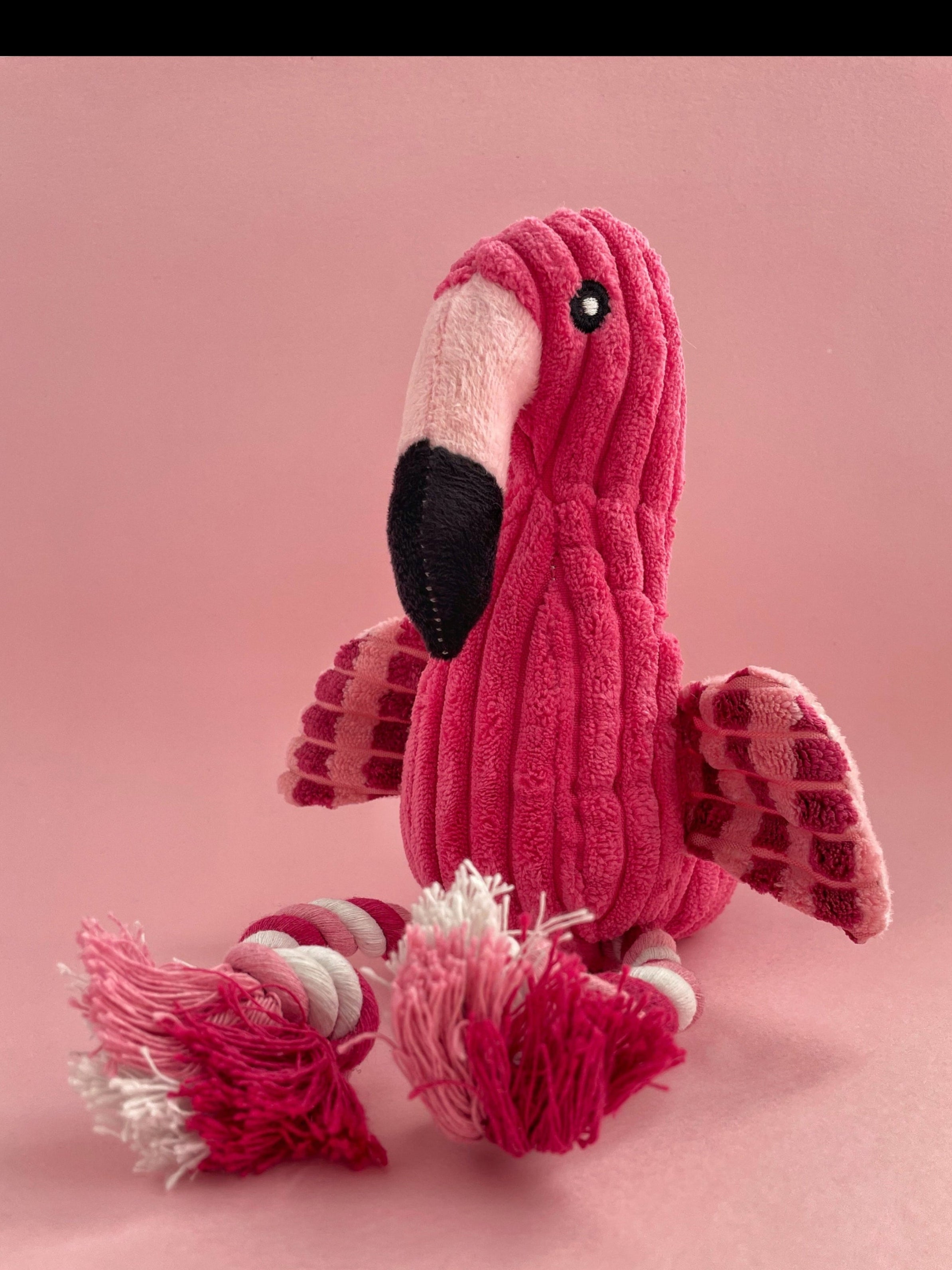Pink plush flamingo toy on a pink background